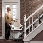Woman stood next to a Stairlift - Stairlifts, Stairlift repairs, stairlift rentals in Cirencester, Newbury, Malmesbury,